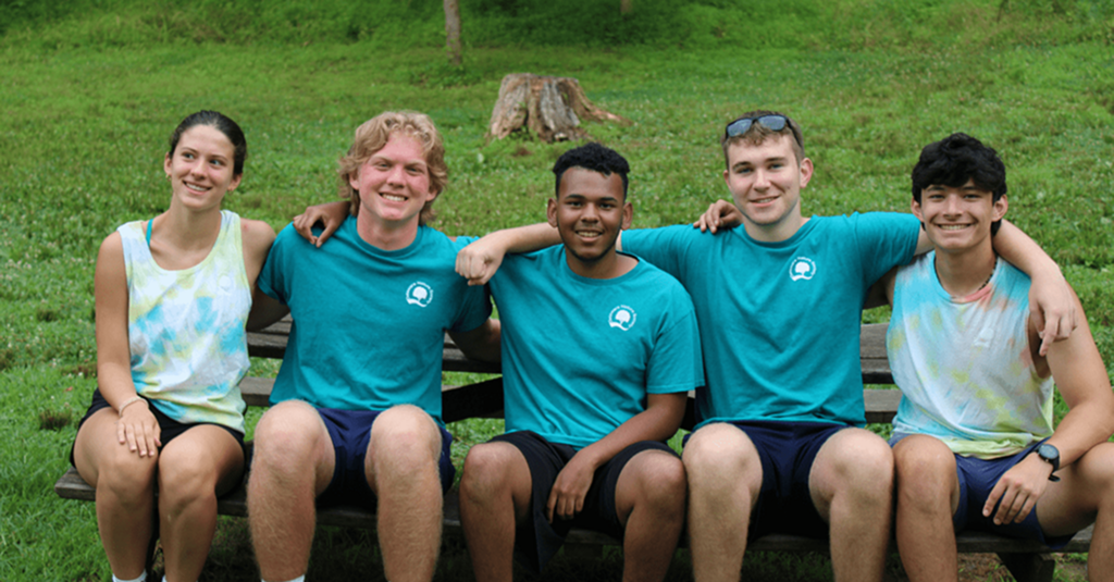 Four young people smiling together outdoors.